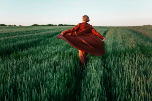 Woman in red coat walking in the field at sunset, 2017