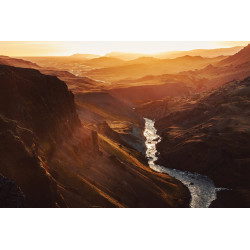 Iceland valley with golden light and mountain silhouettes.
