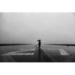 Lone person with umbrella in the rain on runway