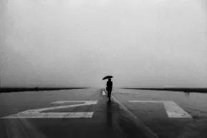Lone person with umbrella in the rain on runway, 1948